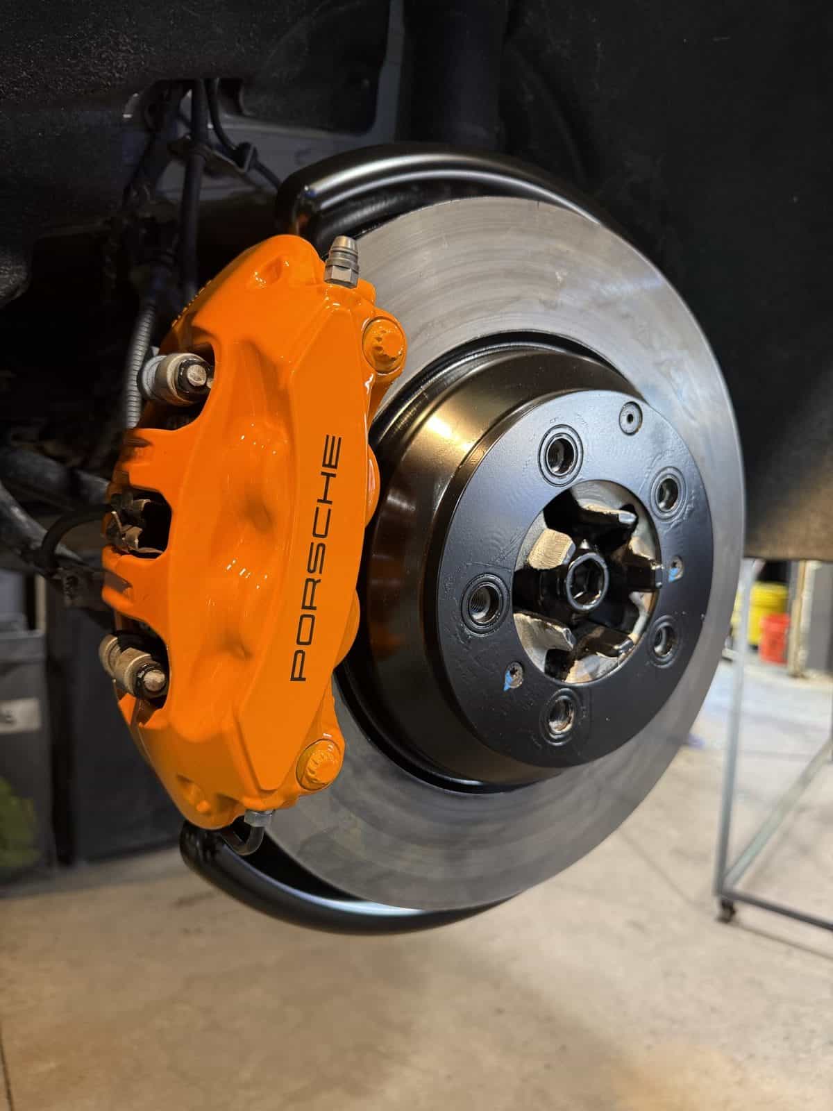 Porsche brake caliper after powder coating - orange side view by ColorWerks Denver