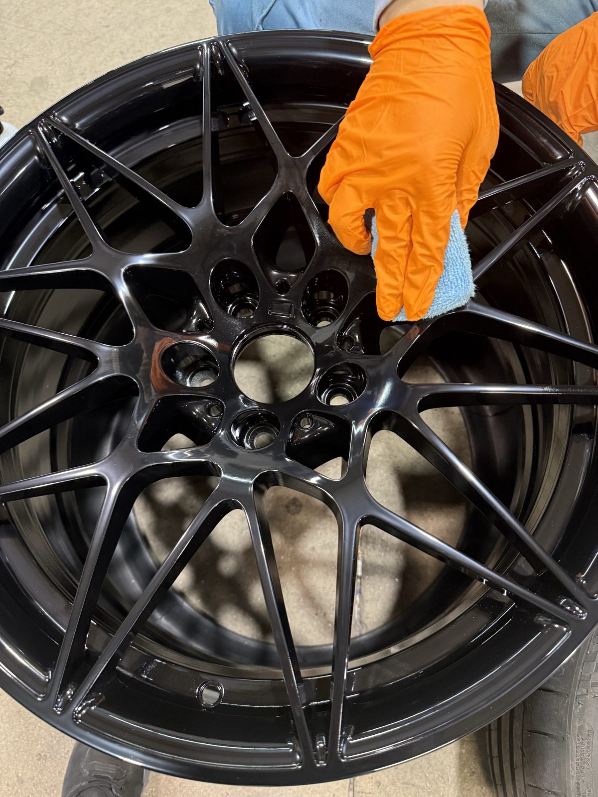 Finished gloss black multi-spoke wheel being wiped down before pickup