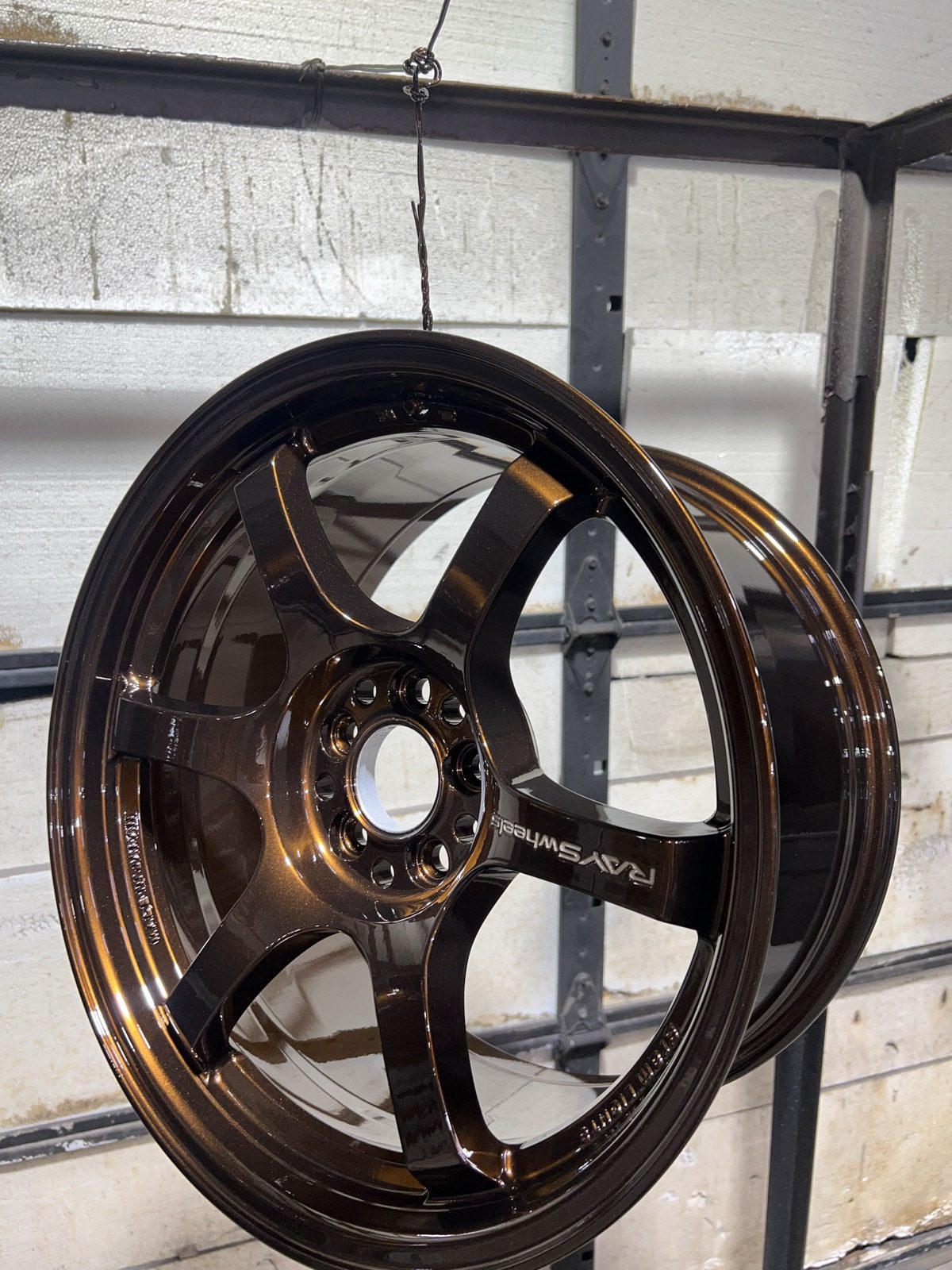 Finished wheel in a gloss metallic bronze powder coat hanging in the shop