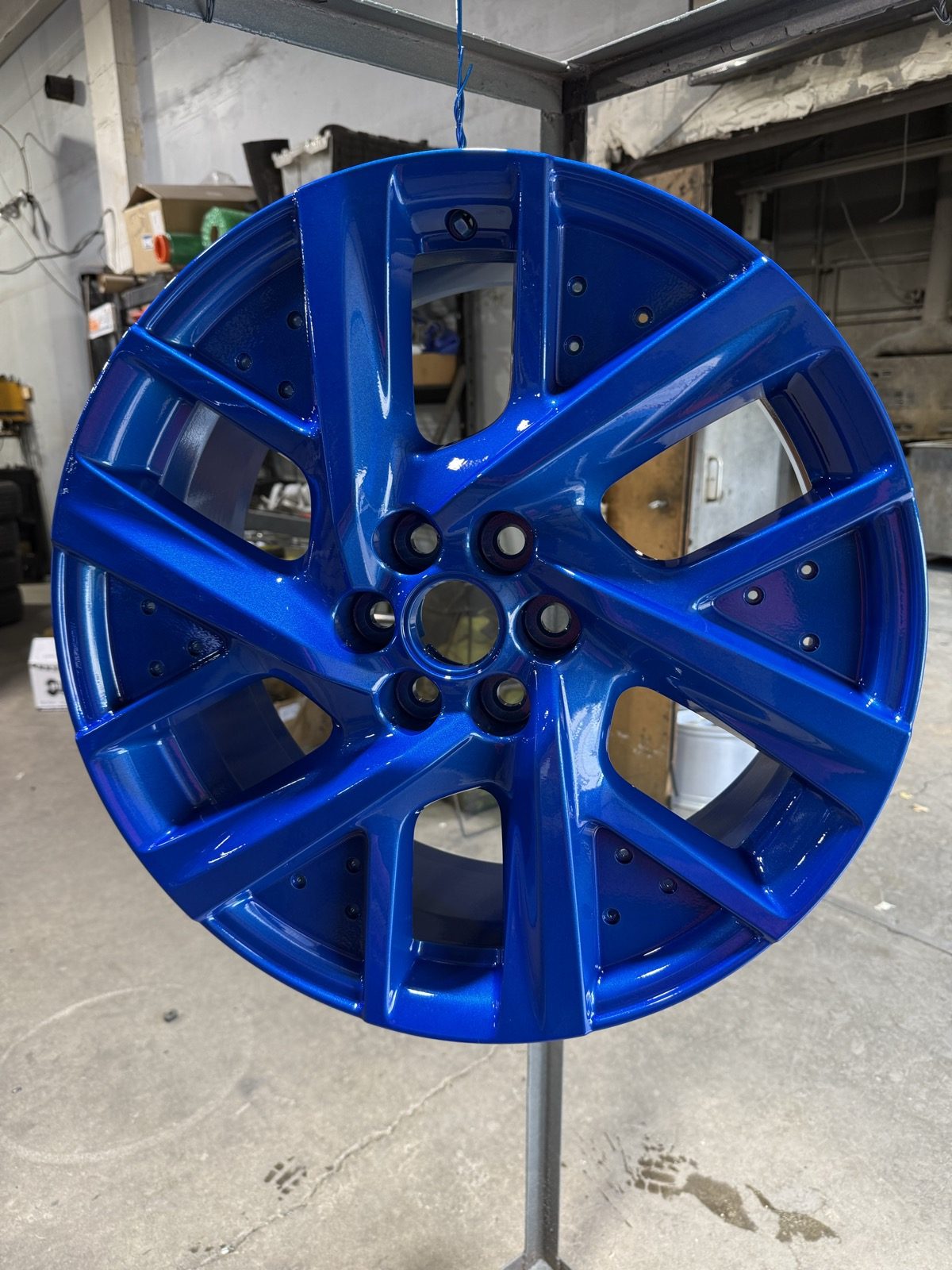 Metallic blue powder coated wheel hanging in the shop