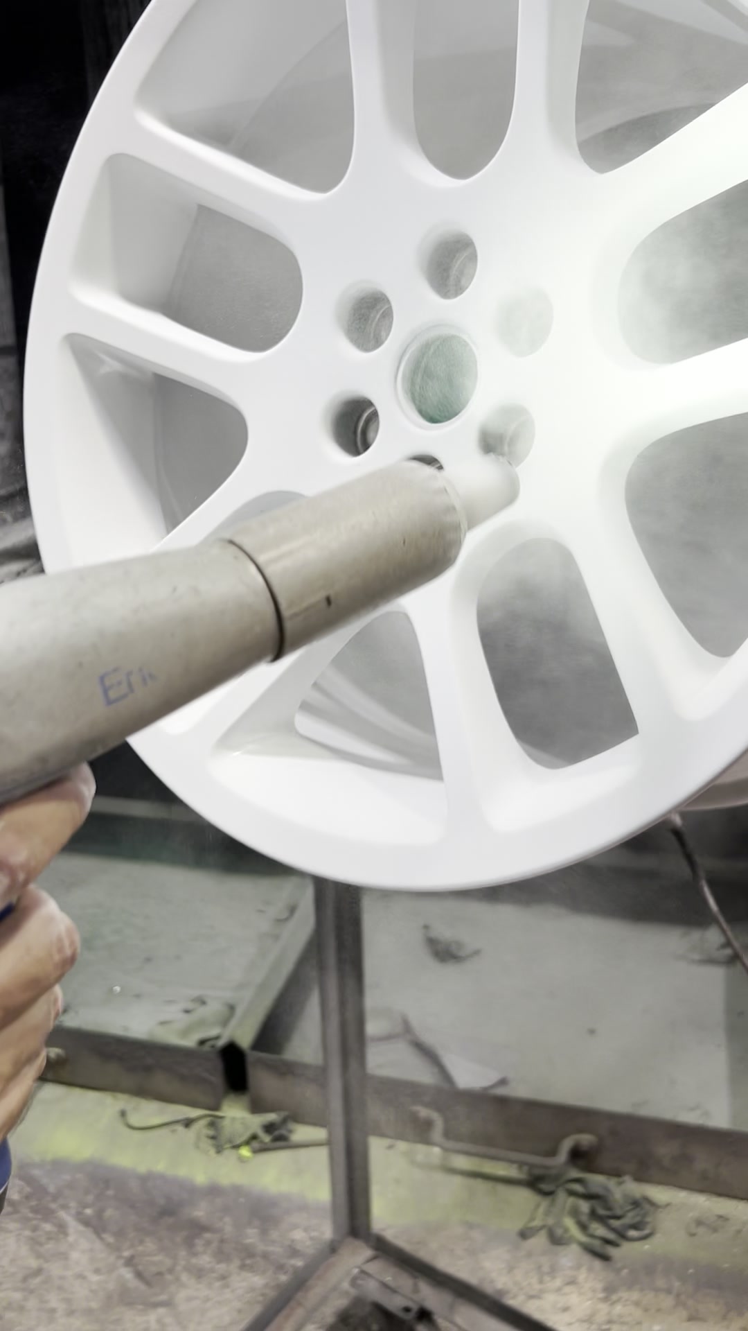 White powder being applied to a wheel in the spray booth before the oven cure