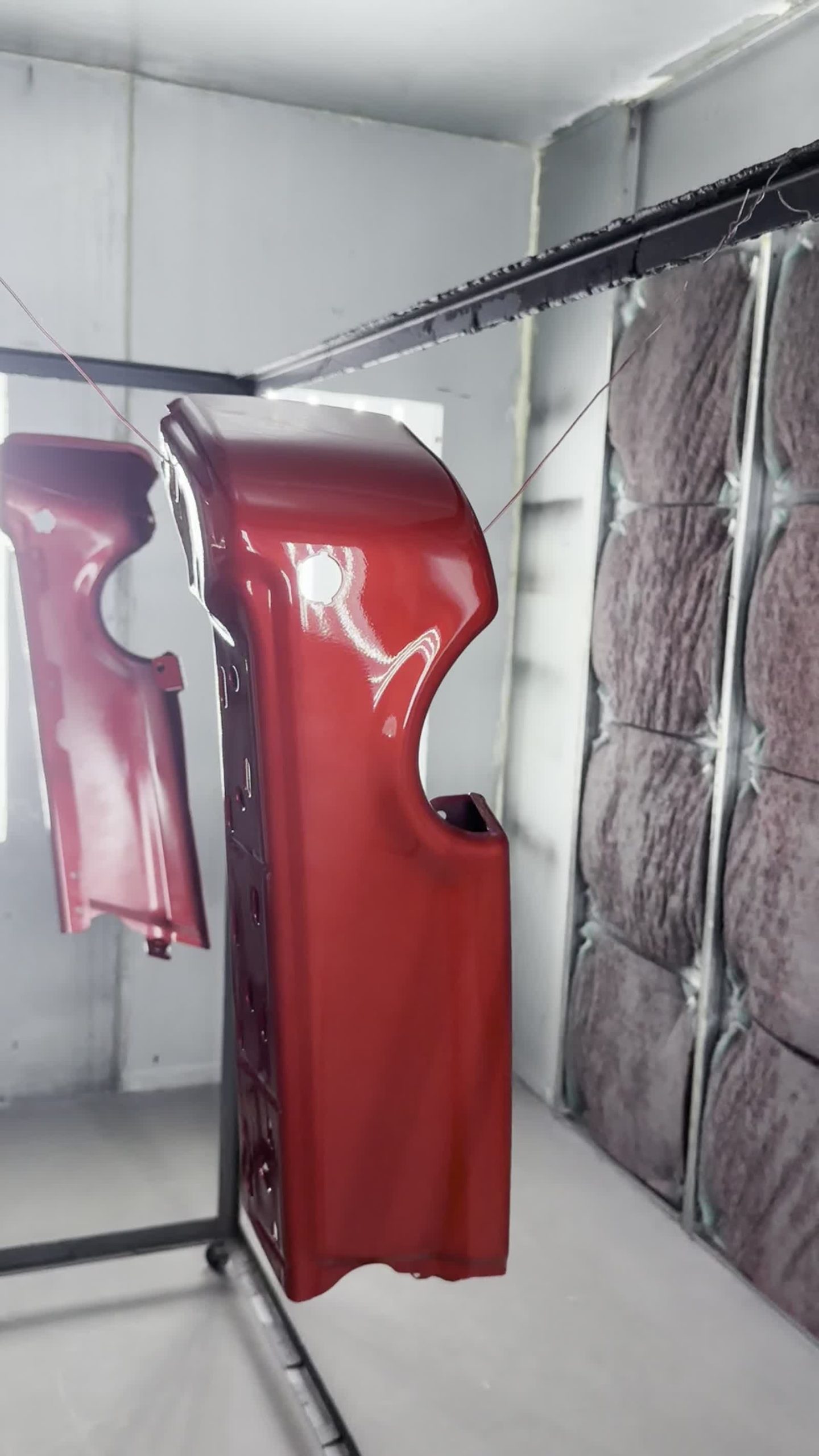 Freshly painted gloss red body panels hanging in the ColorWerks paint booth